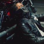 Tired rider resting against motorcycle